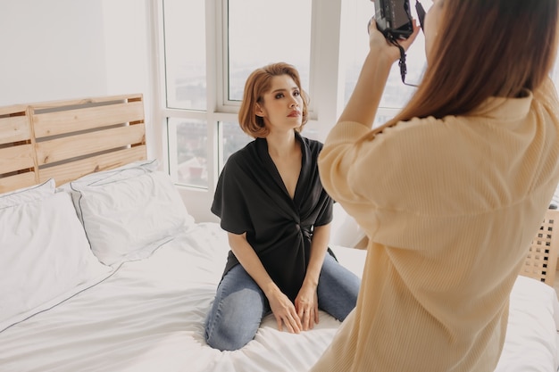 Woman photographer is taking a photo of her woman fashion model