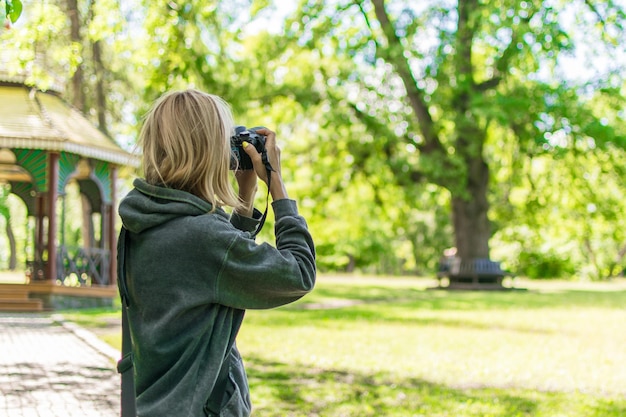 Женщина-фотограф фотографирует в зеленом лесу летом