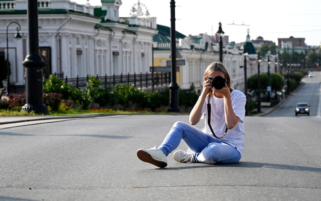 手にカメラを持った女性写真家が街の通りを歩く 女性写真家が手にカメラを持って街の通りを歩く