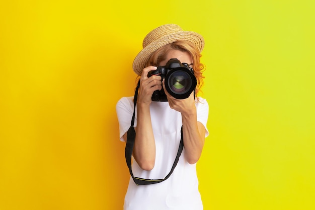 Woman photographer with camera in straw hat making photo, lens.