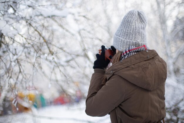 冬の雪の中でレトロなカメラを持つ女性写真家