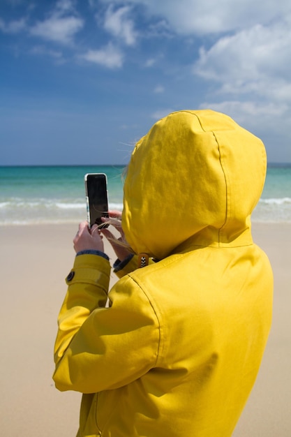 写真 空に向かってビーチで写真を撮っている女性