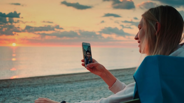 Foto donna che fotografa sulla spiaggia contro il cielo