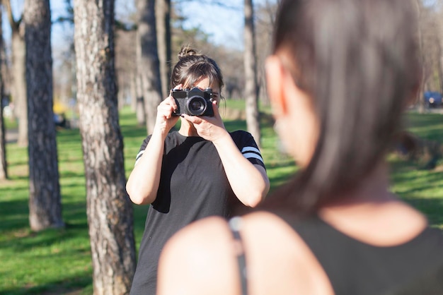 Фото Женщина фотографирует подругу в парке.