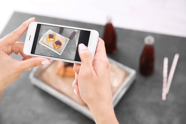 写真 スマートフォンで食べ物を撮影する女性