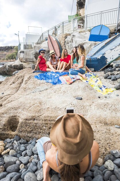 Foto donna che fotografa amici sulla spiaggia contro il cielo