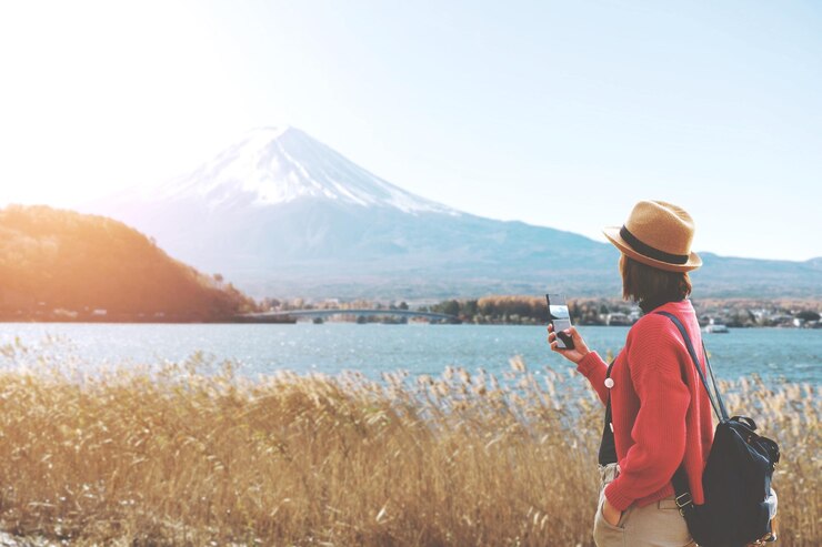 Photo 空を背景に湖と山を撮影する女性
