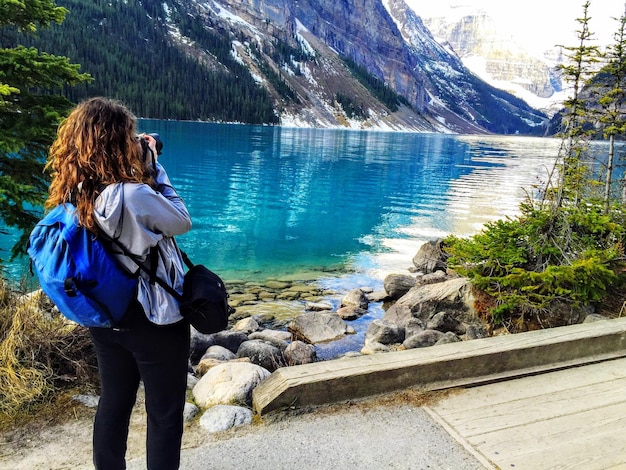 Woman photographing lake with camera
