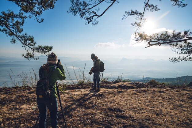 写真 空に照らされた山の上で男性を撮影している女性