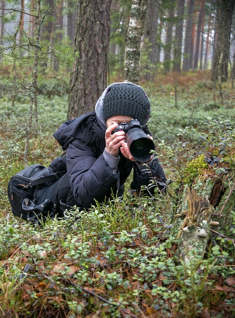 Женщина фотографирует растение в лесу