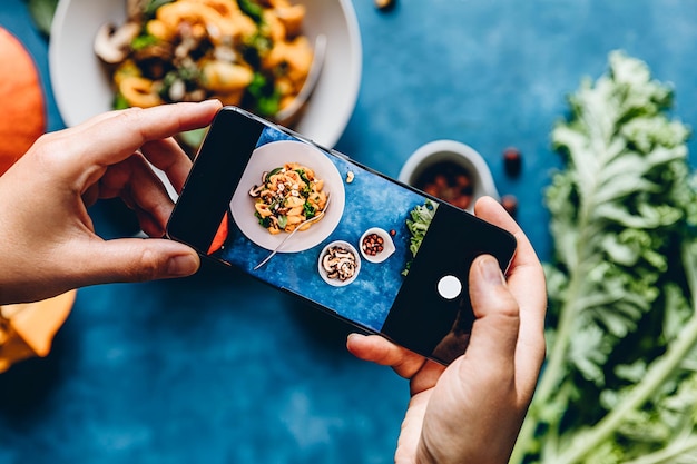 Photo woman photographing pumpkin pasta dish