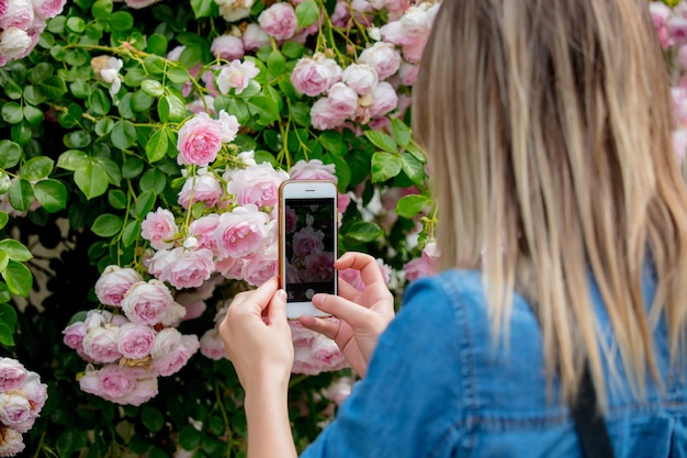 Photo woman photographing a rose using the phone. side view