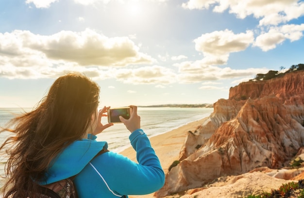 Foto donna che fotografa il mare contro il cielo