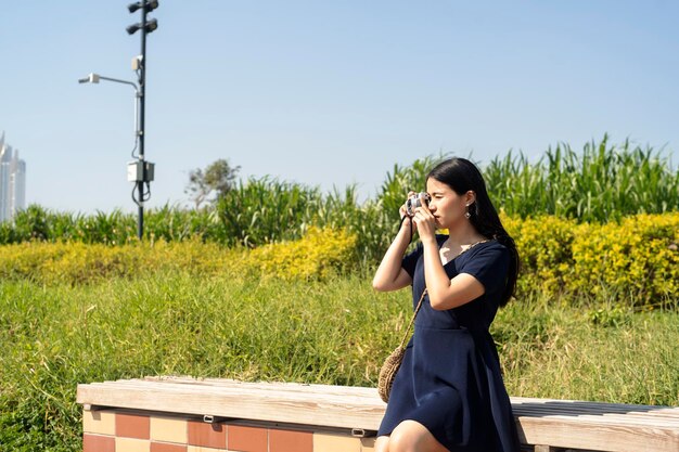 Woman photographing while sitting at park