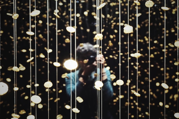 Photo woman photographing while standing amidst illuminated lights at night