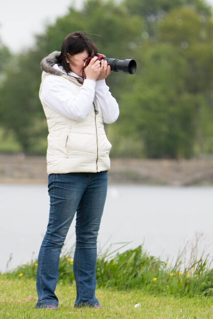 写真 草原の川のそばに立っている女性が写真を撮っている