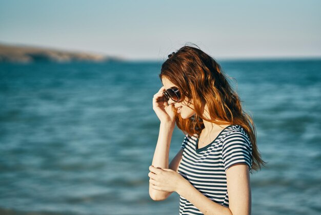 Woman photographing while standing by sea against sky