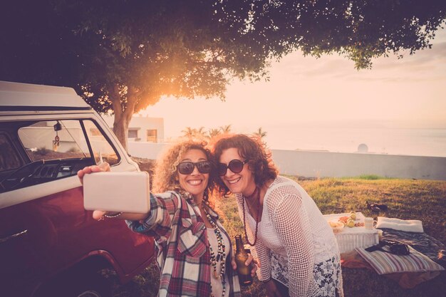 写真 夕暮れの空に向かって携帯電話で写真を撮っている女性