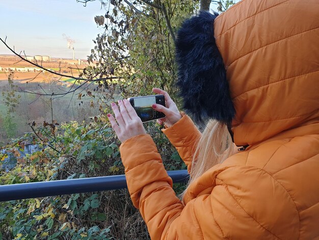 Photo woman photographing with mobile phone during winter