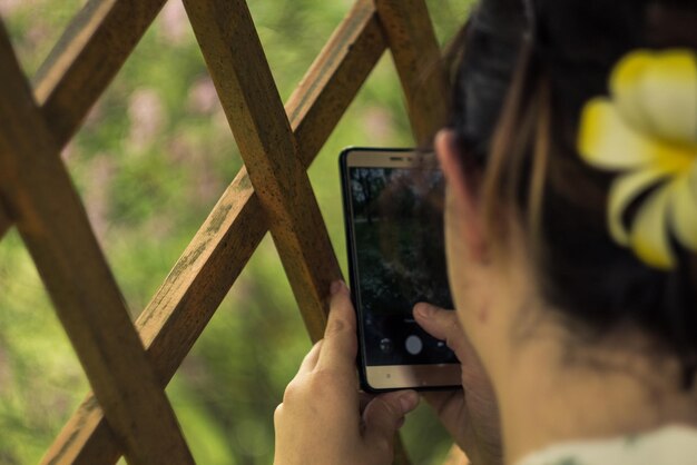 写真 窓から携帯電話で写真を撮っている女性