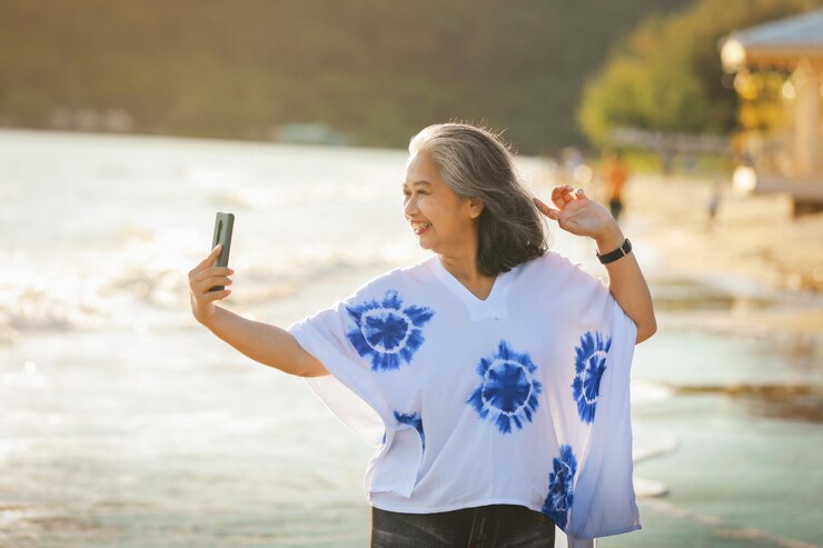Photo ビーチに立っている女性が携帯電話で写真を撮っている
