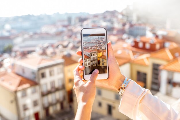 Donna che fotografa con la vista del paesaggio urbano del telefono sulla città vecchia della città di porto in portugal