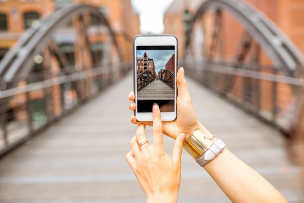 Woman photographing with smartphone old iron bridge in Hamburg, Germany