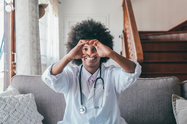 Woman physician doing heart shape gesture with hands Smiling black female doctor making a love symbol using her hands Healthcare worker expressing love and support to patients