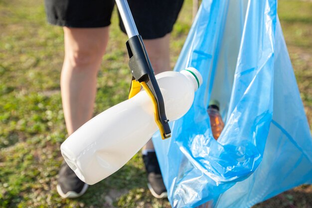 Woman picking the plastic bottle by the garbage picking\
tool