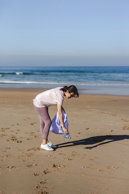 Woman picking up trash and plastics cleaning the beach