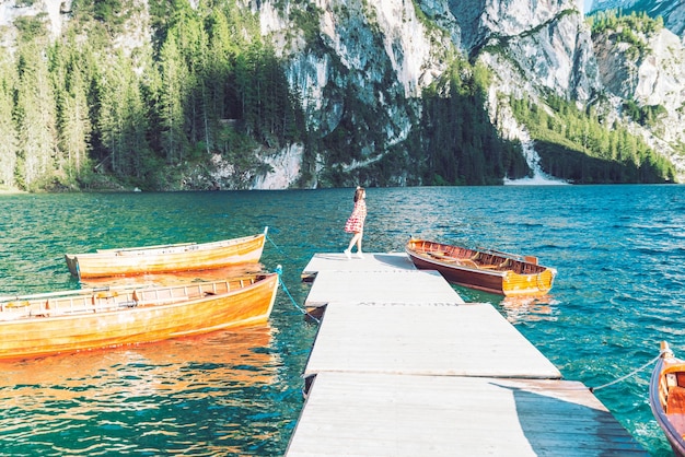 Woman at pier with wooden boats in mountain lake in italy