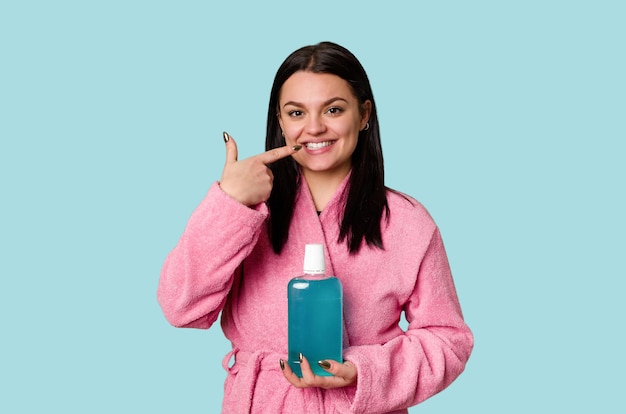 Woman in pink bathrobe holds a bottle of mouthwash promoting the importance of oral hygiene