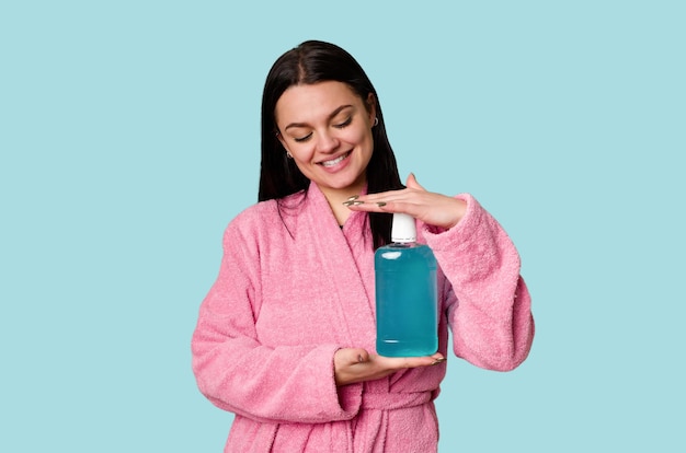 Woman in pink bathrobe holds a bottle of mouthwash promoting the importance of oral hygiene