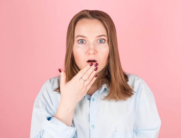 Woman on pink in blue shirt doing oops gesture