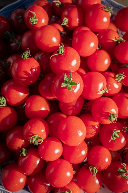 Woman in pink dress holding a plate full of fresh red cherry tomatoes