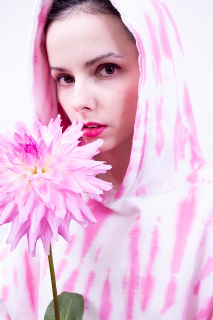 woman in a pink hoodie holds a large pink flower in her hand