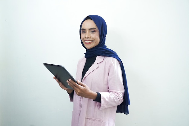 A woman in a pink jacket is holding a tablet in her hand.