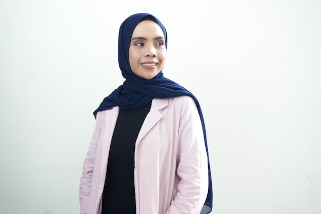 A woman in a pink jacket and a pink jacket stands in front of a white wall.