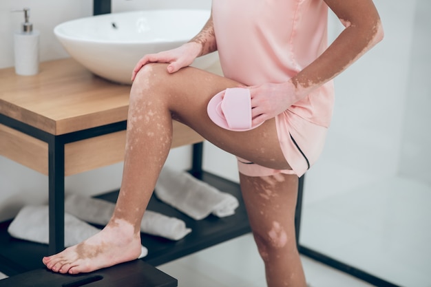 A woman in pink lingerie massaging her thighs