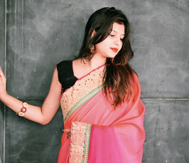 woman in pink sari while standing against wall