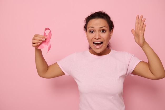 Woman in pink t-shirt holding cancer awareness pink ribbon.
october breast cancer awareness month, woman in pink t- shirt with
pink ribbon for supporting people living and illness.