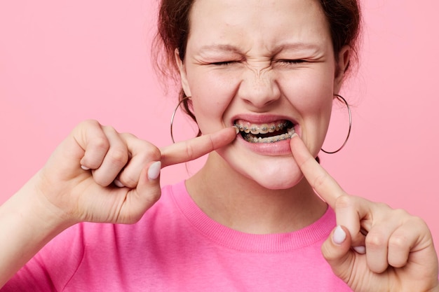 Photo woman in pink tshirt braces posing pink background