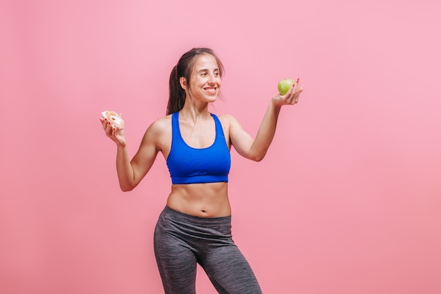 woman on a pink wall holding a cake and an Apple