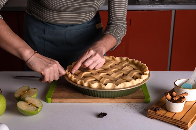 パン屋の皿にリンゴパイの上にパイの生地を置く女性 オーブンに入れる準備ができている リンゴパイの準備 感謝祭のケーキの準備 秋のパン屋 脆い天気の甘いもの レシピ
