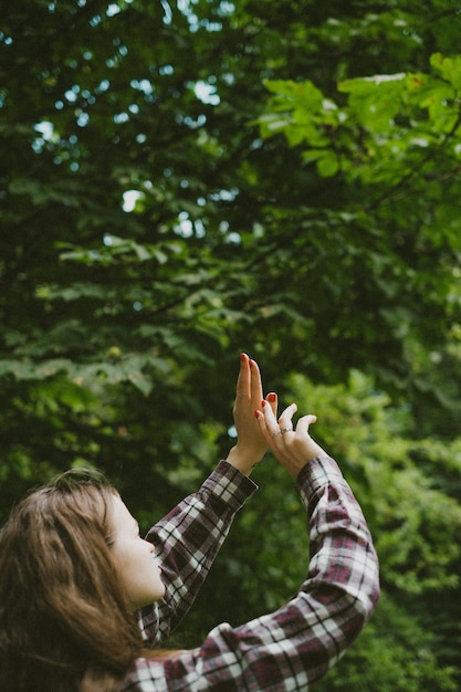 Photo a woman in a plaid shirt reaching up to catch a leaf photo