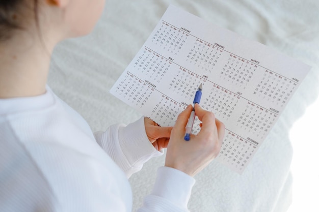 Woman planning her monthly menstruation calendar mark the days of menstruation and ovulation