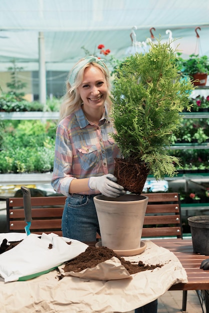 Woman planting a bush in flower pot using dirt in garden center