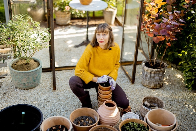 庭で水差しに花を植える女性