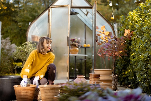 庭で水差しに花を植える女性