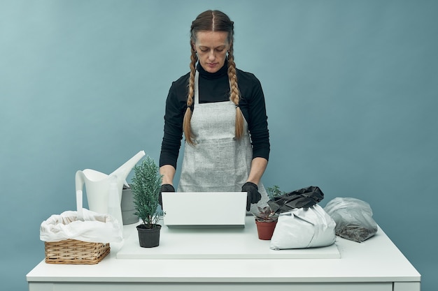 Woman plants indoor plants and flowers in soil and pots